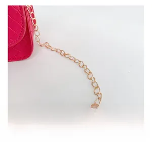 Gros plan sur la texture tressée fuchsia et la chaîne dorée du sac à bandoulière enfant