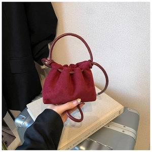 Dettaglio di una borsa a secchiello in pelle scamosciata bordeaux con coulisse per bambini