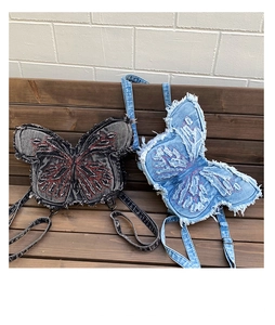 Detail of vintage denim backpacks with butterfly embroidery and frayed edge textures