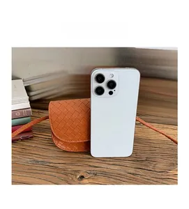 Caramel woven mini crossbody bag size comparison with a white smartphone on wood