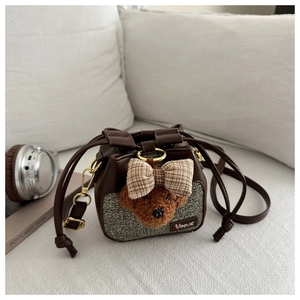 Dettaglio di una mini borsa a secchiello in tweed marrone con orsetto e coulisse