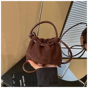 Dettaglio di una mini borsa marrone in pelle scamosciata con coulisse e manico in pelle