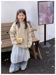 Fille en pull beige avec un sac à bandoulière doré élégant orné d'un petit nœud chic