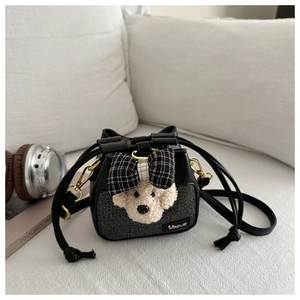 Dettaglio della mini borsa a secchiello con mascotte cane di peluche su sfondo minimal