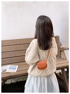 Close-up of brown woven mini crossbody bag with textured semi-circular bottom and strap