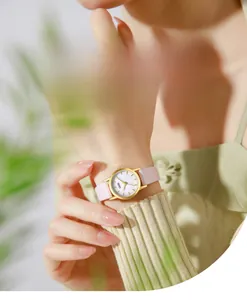 Close-up of mother-of-pearl dial quartz watch with pink leather strap on woman's wrist