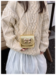 Détail d'un mini sac à bandoulière doré avec texture tressée et un nœud décoratif