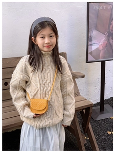 Close-up of bright yellow quilted crossbody bag styled with beige cable knit sweater