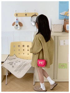 Fillette portant un mini sac bandoulière rose matelassé avec boucle nœud doré