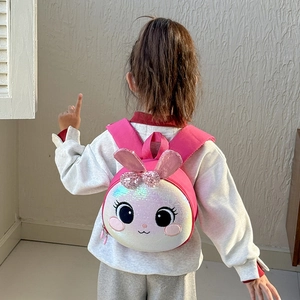 Pink glitter rabbit ears kids hardshell backpack worn by a young girl on light background