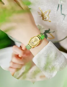 Detail of Gedi gold oval watch with green leather strap and sunray dial on wrist