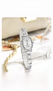 Detailed shot of oval dial quartz watch with silver denim chain strap and sunburst pattern