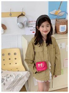 Petit sac bandoulière rose matelassé avec nœud doré porté par une petite fille élégante