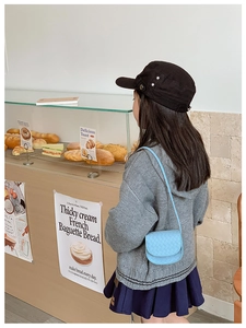 Toddler in grey sweater wearing sky blue quilted crossbody bag in a cozy bakery shop