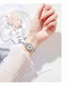 Close-up of elegant silver oval watch with cuban chain bracelet on a woman's wrist