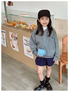 Detail of kids grey hooded knit sweater with M embroidery and navy pleated skirt