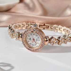 Gros plan d'une montre à quartz rose doré avec lunette sertie de diamants et cadran blanc