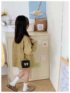 Gros plan d'un sac à bandoulière matelassé noir pour enfant avec boucle dorée en nœud