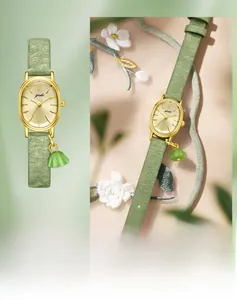 Detail of golden oval watch with green floral pendant on embroidered silk fabric