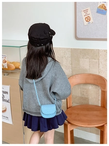 Blue quilted crossbody bag for kids shown on a model in a cozy cafe setting
