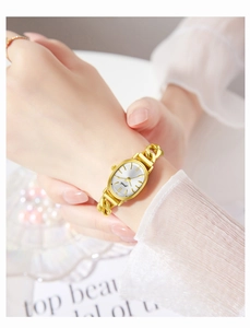 Close-up of elegant gold chain watch with an oval dial worn on a female wrist