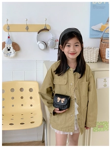 Détail d'un petit sac bandoulière matelassé noir avec nœud doré et chaîne métallique