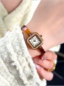 Detail of vintage square gold watch with amber textured strap on model's wrist