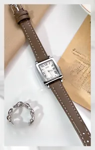 Macro shot of silver square quartz watch with Roman numerals and brown leather strap