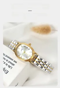 Detail of elegant oval gold watch face with silver sunray dial and bicolor metal strap