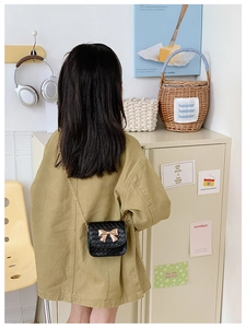 Détail d'un petit sac bandoulière matelassé noir pour enfant avec nœud doré et chaîne