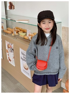 Close-up of a child wearing a red woven mini crossbody bag in a cozy bakery setting