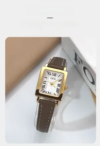 Macro shot of rectangular gold watch case with Roman numerals and brown leather strap