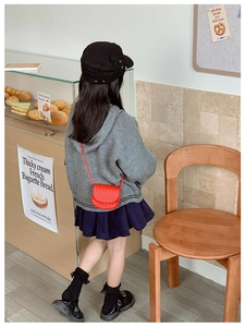 Detail of red quilted mini crossbody bag for kids with woven texture and semicircular flap