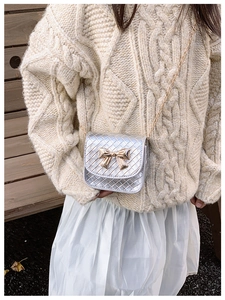 Détail du petit sac argenté matelassé avec nœud doré et bandoulière en chaîne