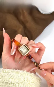 Detailed shot of retro gold square watch with pearl dial and amber-textured chain strap
