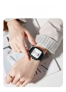 Close-up of GEDI square black quartz watch with white dial on wrist with props