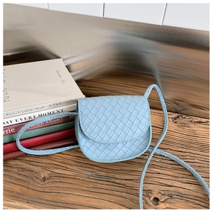 Close-up of light blue quilted mini crossbody bag featuring fine woven texture and saddle shape
