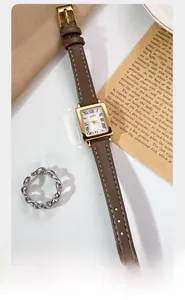 Retro square watch with brown leather strap displayed on vintage paper and soft fabric