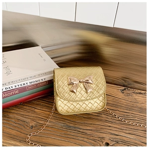 Détail d'un mini sac tissé or champagne avec nœud rose doré et bandoulière chaîne