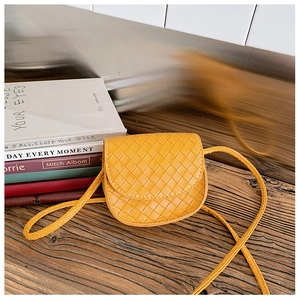 Detail of a ginger yellow woven mini crossbody bag with a quilted PU leather texture