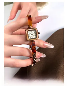 Close-up of Gedi square watch featuring amber resin chain and Roman numeral dial