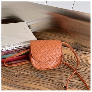 Detailed view of orange woven leather mini crossbody bag for kids on rustic wooden surface