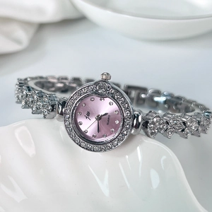 Gros plan d'une montre bracelet argentée sertie de strass avec cadran violet sur plateau