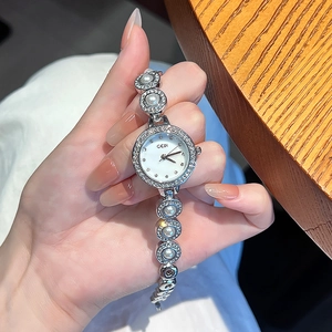 Montre argentée élégante avec bracelet en perles et strass et cadran blanc épuré