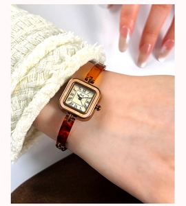 Close-up of vintage square quartz watch with amber tortoise shell strap on a wrist