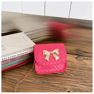 Détail d'un mini sac tissé rose vif avec un grand nœud doré et une bandoulière en chaîne