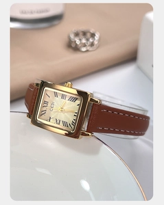 Detailed macro view of a vintage square quartz watch with a brown leather strap