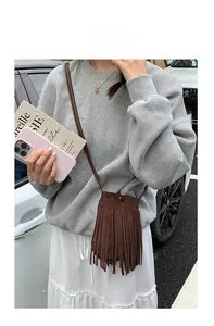 Gros plan du mini sac à bandoulière en daim marron avec pompons et bouton-pression en métal