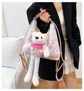 Detail of pink cartoon plush bear handbag with leather strap and golden chain accent