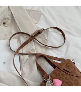 Detail of leopard print handbag with pink heart charm on a beige trench coat